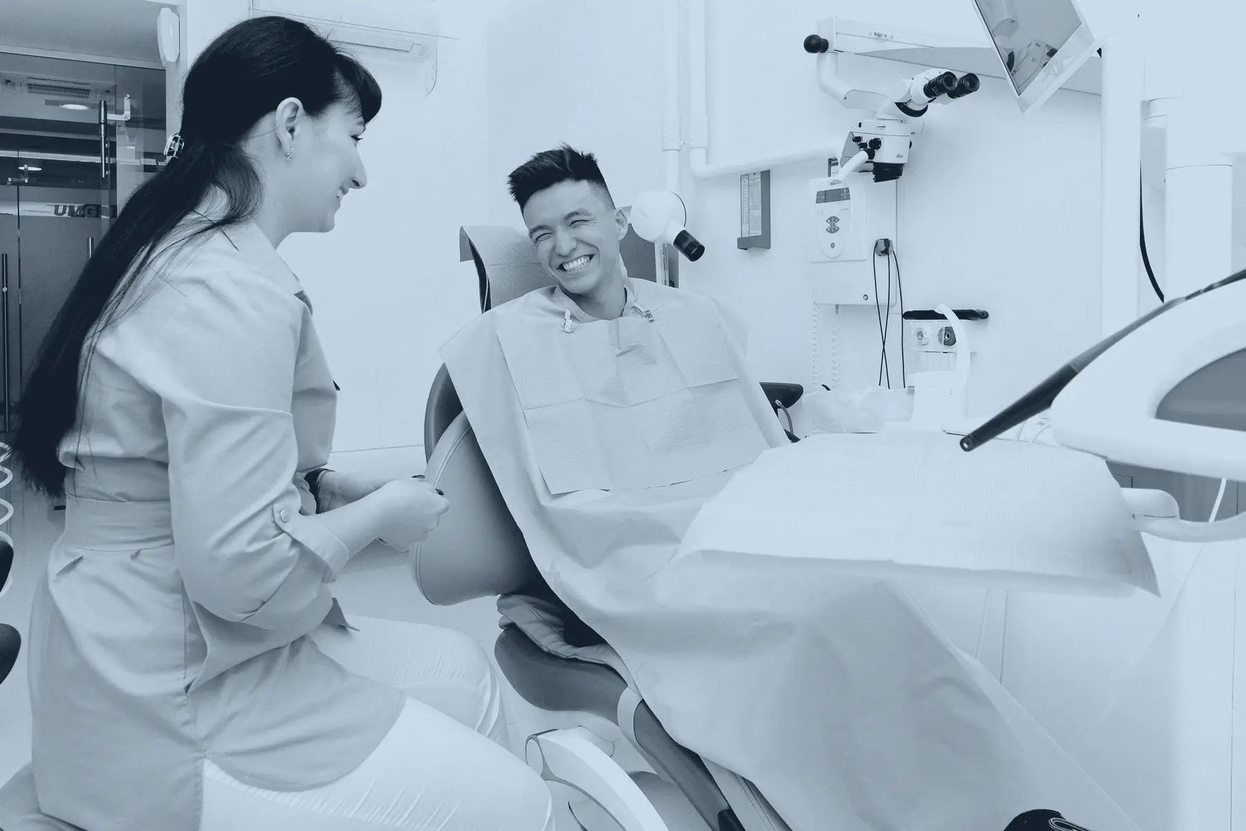 Dentista platica con un paciente sonriente sentado en el sillón dental