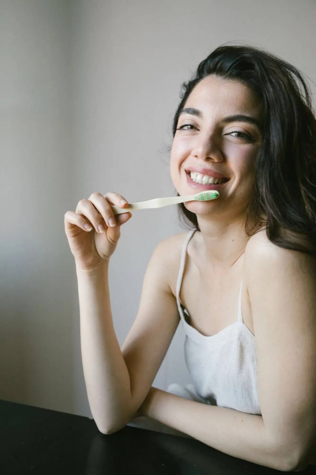 Mujer sonriente sostiene un cepillo de dientes de bambú